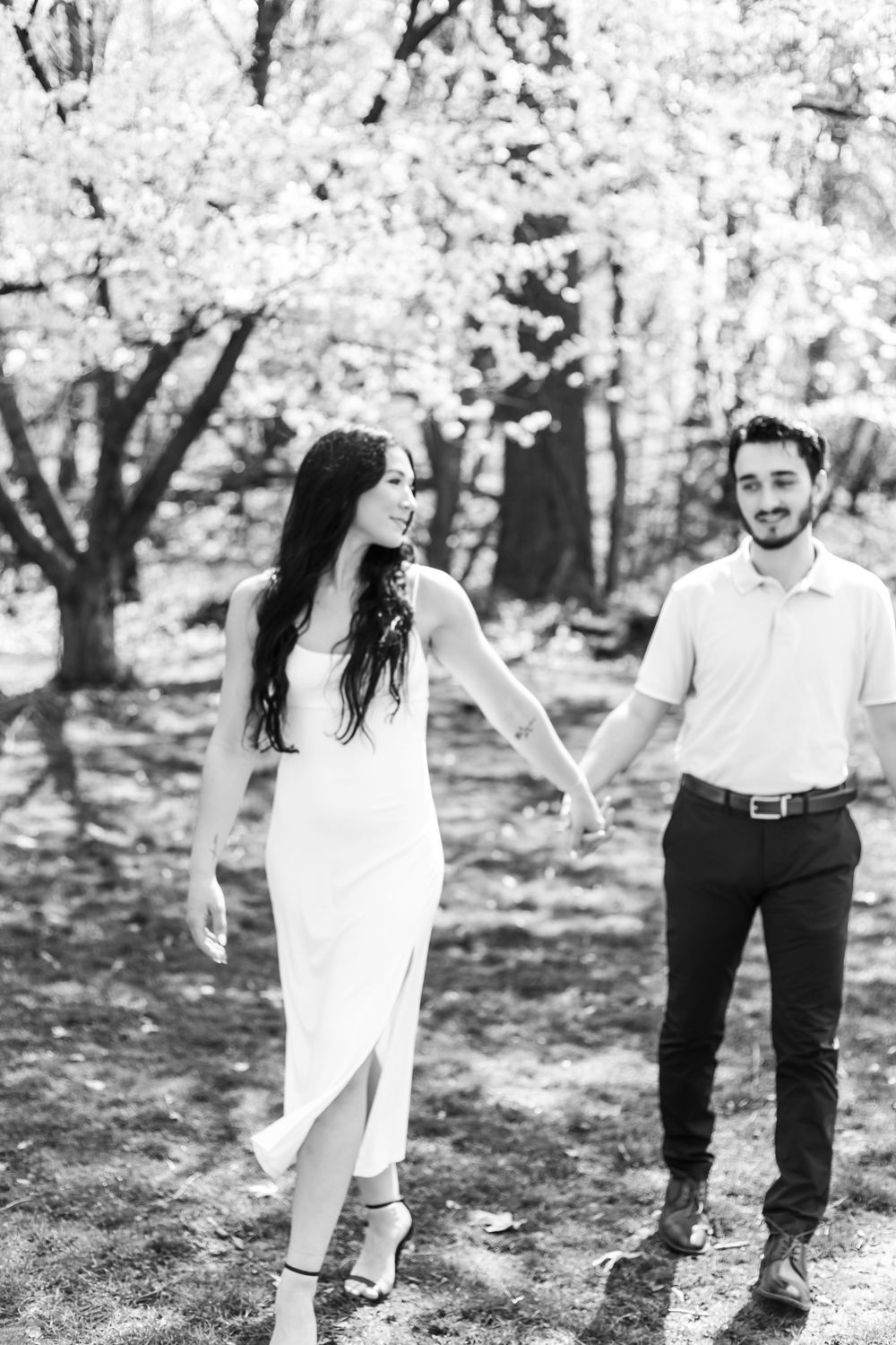 Black and white photo of a couple enjoying a playful moment in a spring garden.