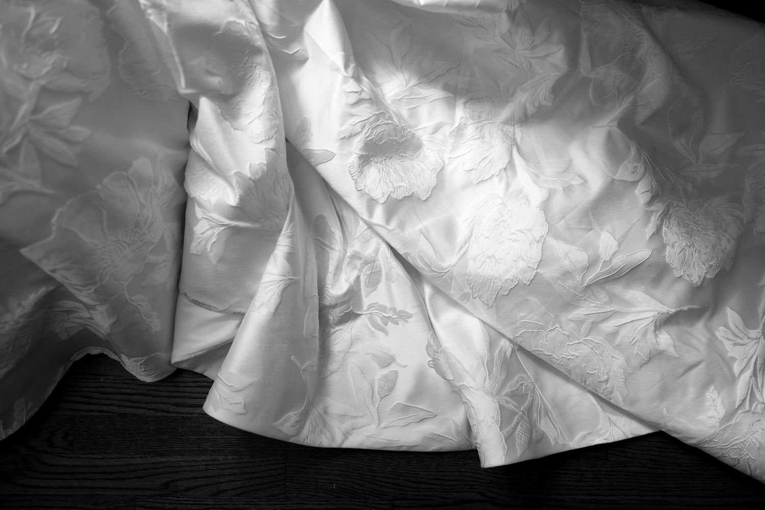Textured white wedding dress with dramatic shadows cast across its surface in black and white.