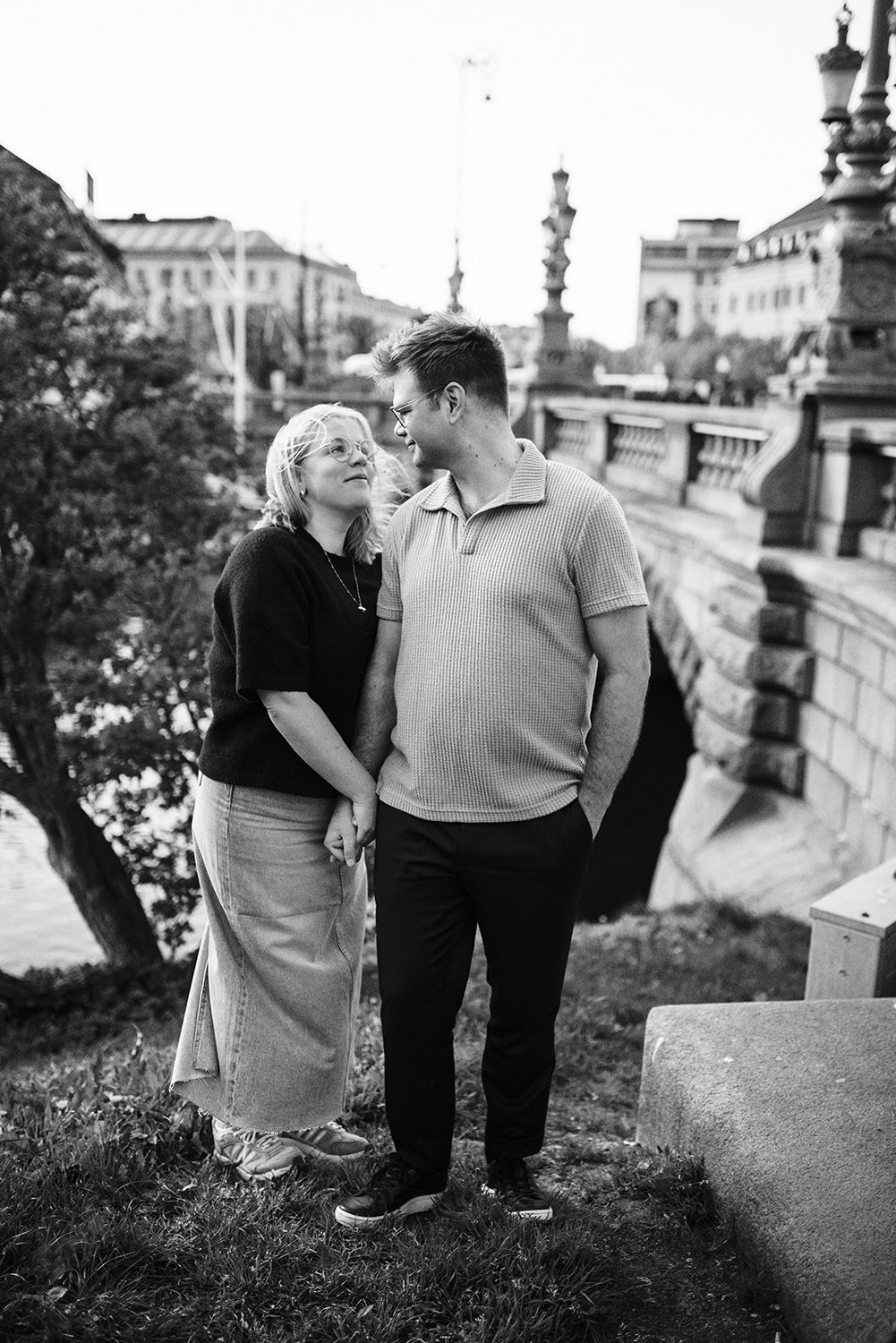 Black and white romantic photo of a couple sharing an intimate moment on stone steps of a grand European-style building.
