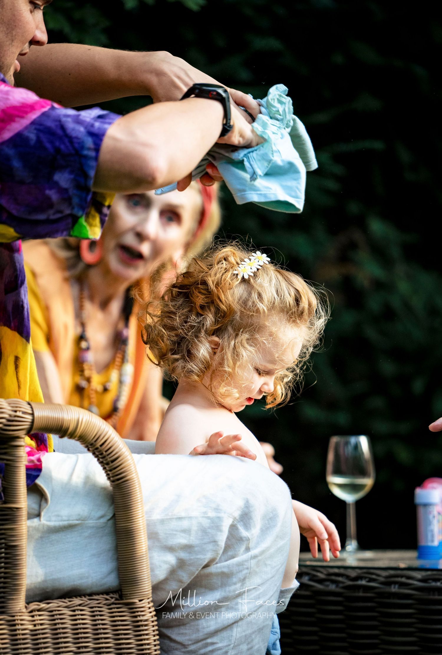 A candid moment at an outdoor dinner gathering with people seated around a wicker table.