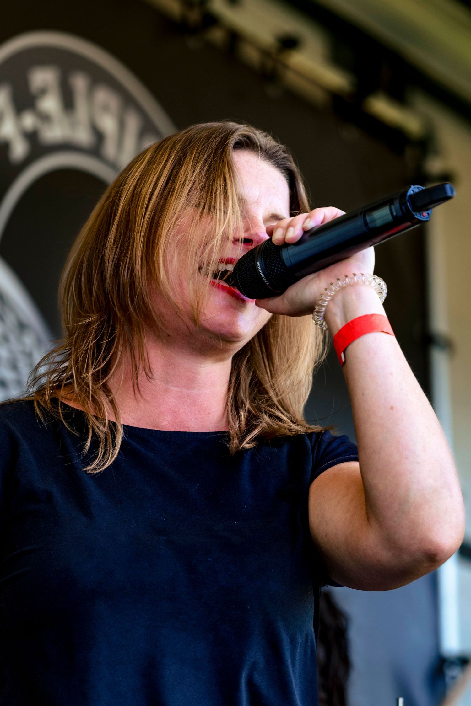 Performer singing into microphone on dark stage.
