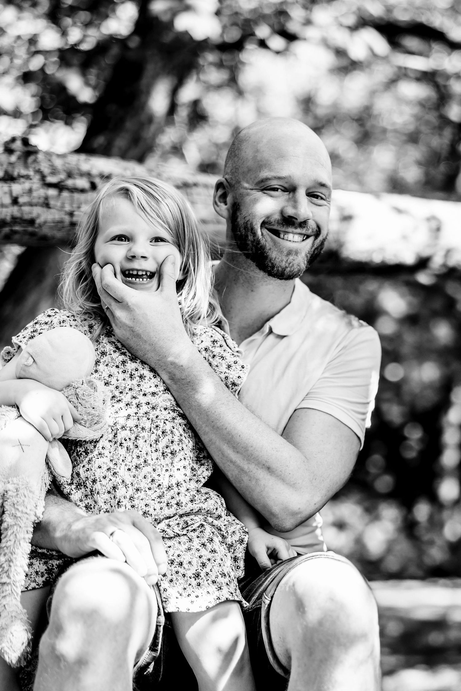 A joyful black and white candid portrait of a parent and child sharing a laugh outdoors.