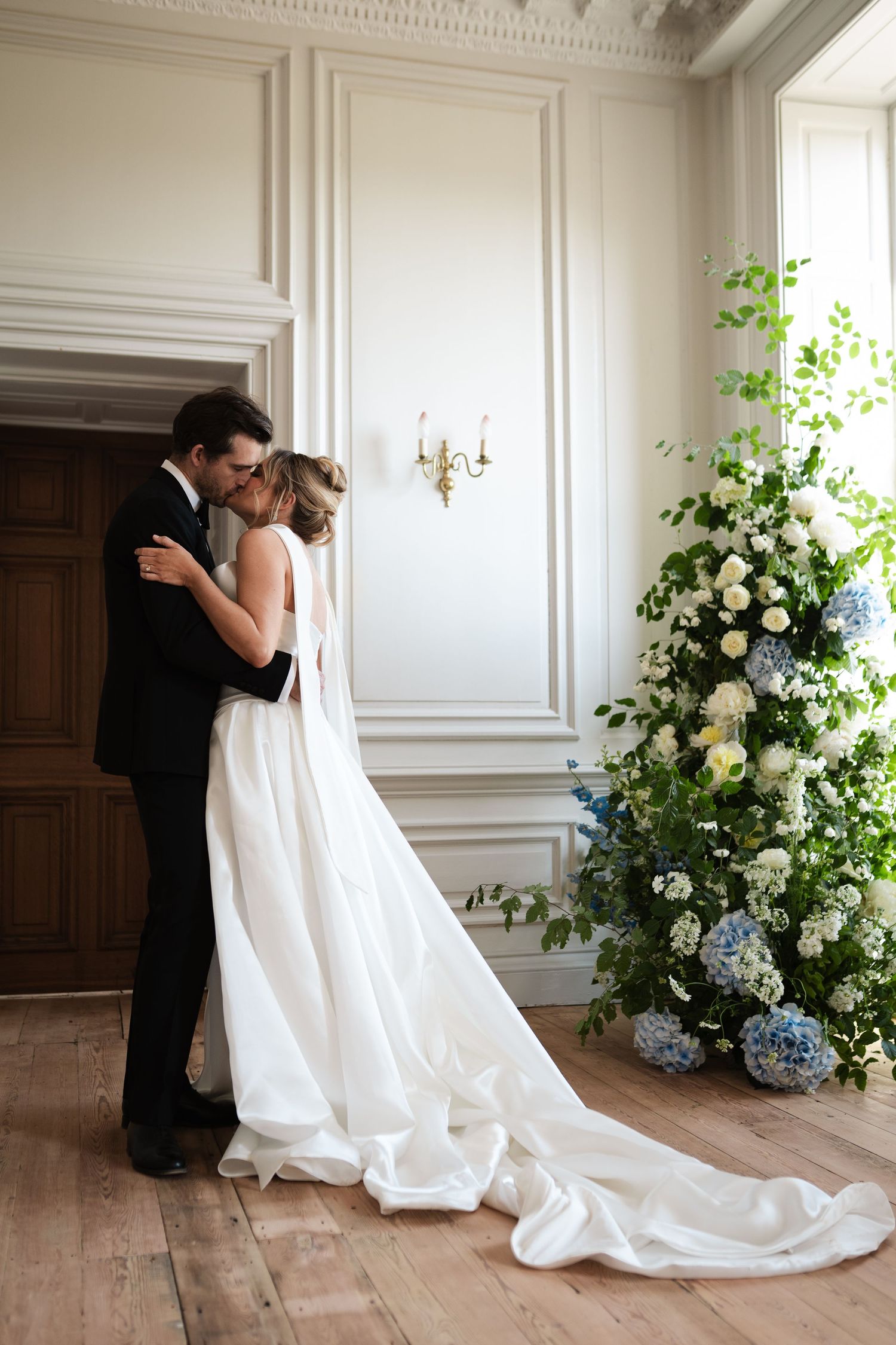 Romantic scene in elegant room with floral arrangements and ornate white wall panels.