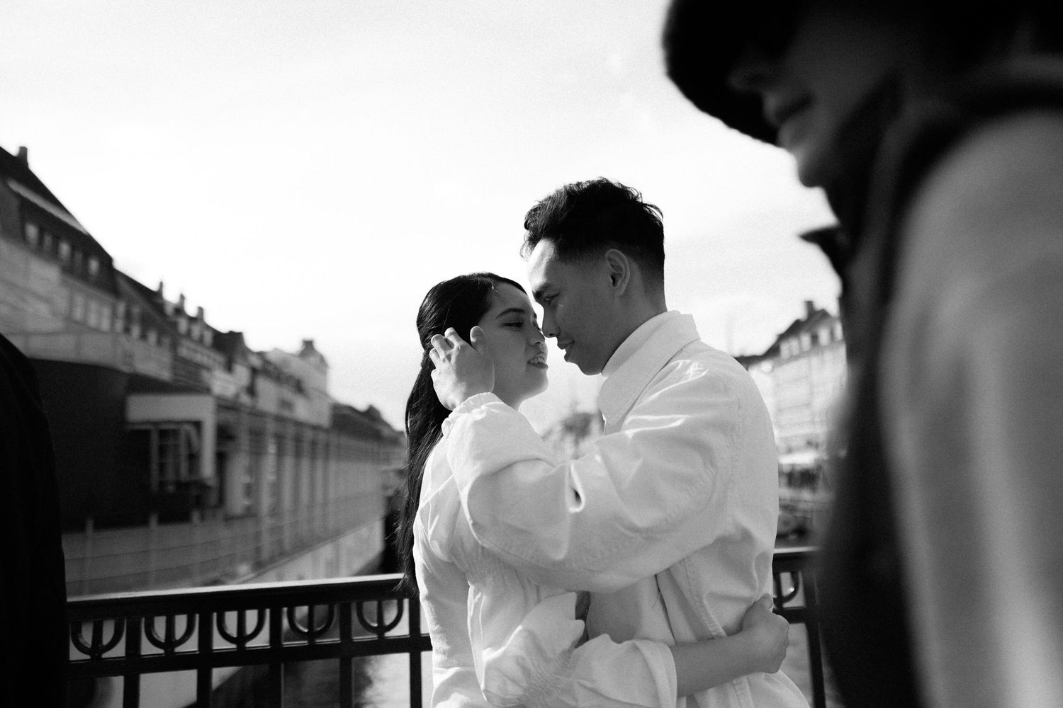 An intimate black and white portrait of a couple embracing on a city balcony. Wedding in Copenhagen, Denmark.