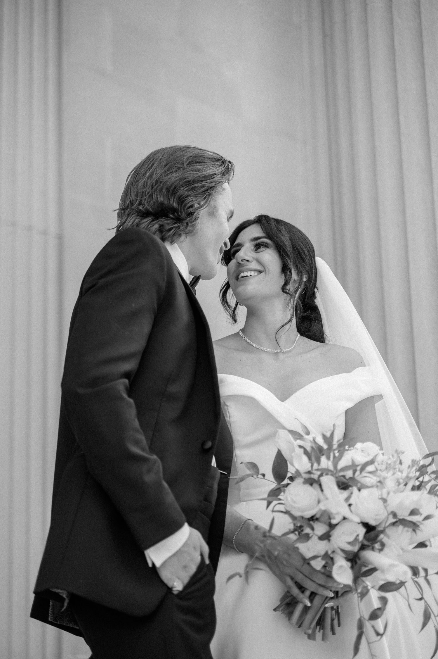 Black and white picture with upward angle of bride smiling at her groom
