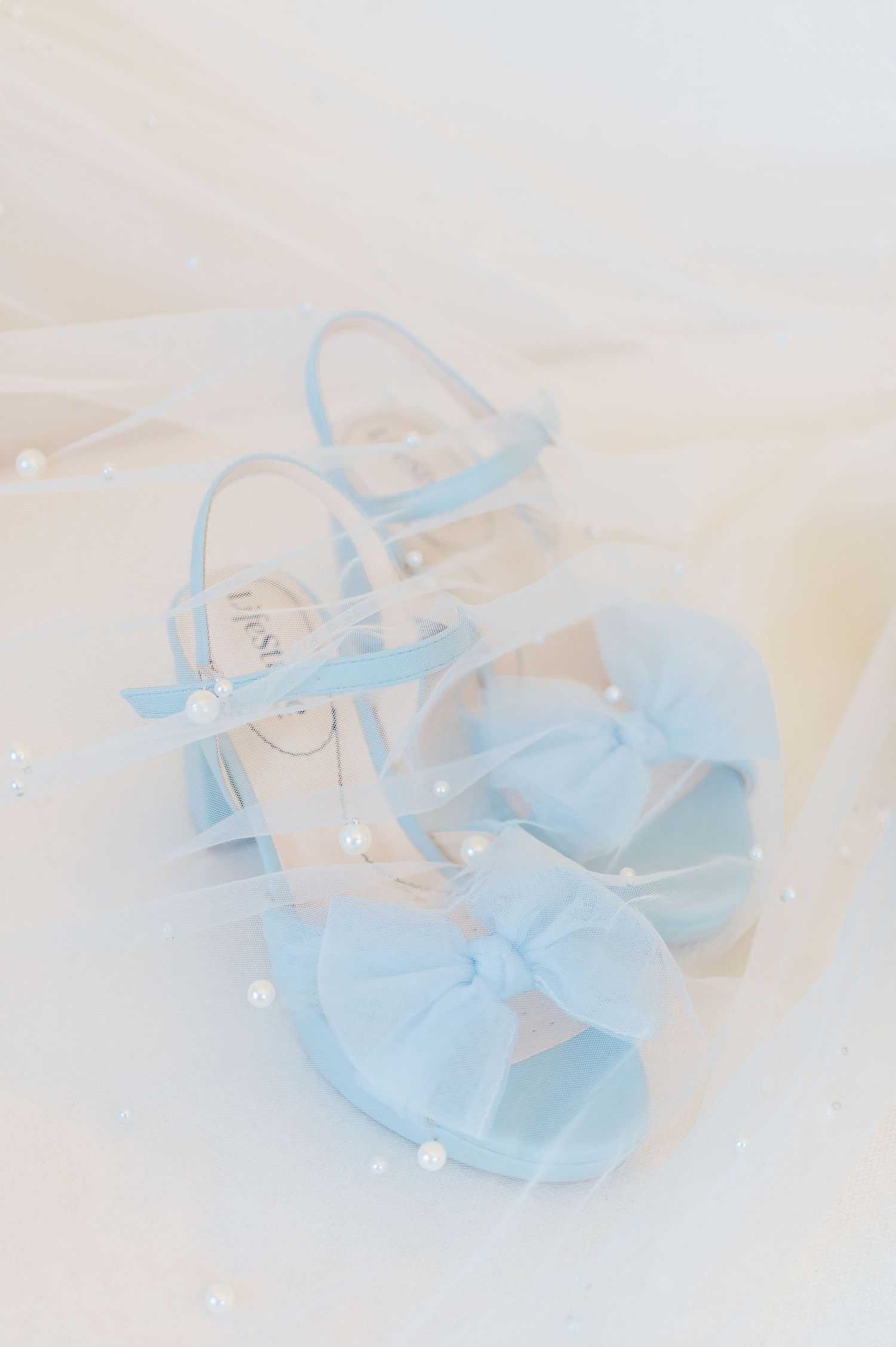 blue heels with bow on top under veil with pearls
