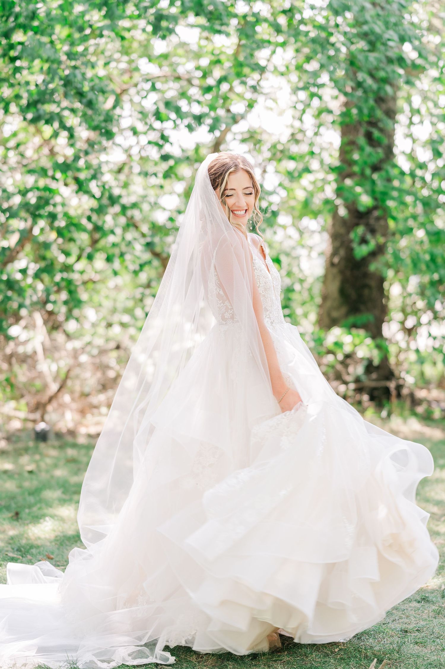 Bride with a big white wedding dress and long cathedral veil smiling down her shoulder
