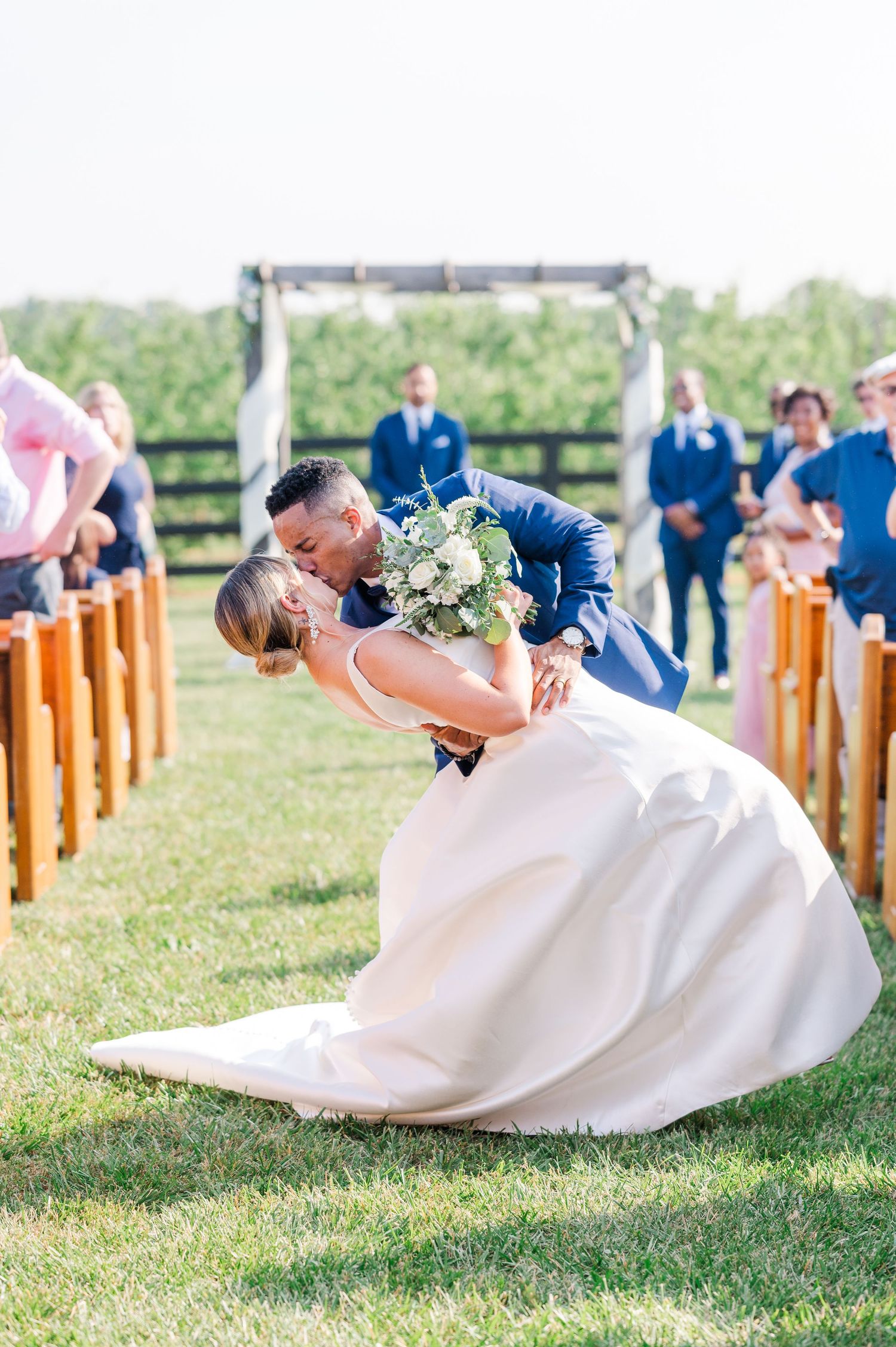 Groom dipping the bride for a mid aisle kiss after wedding ceremony in the summer