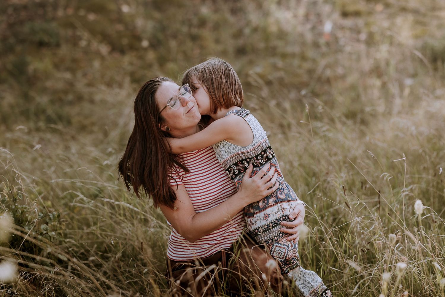 Candid moment of parent and child sharing an embrace in a natural outdoor setting.
