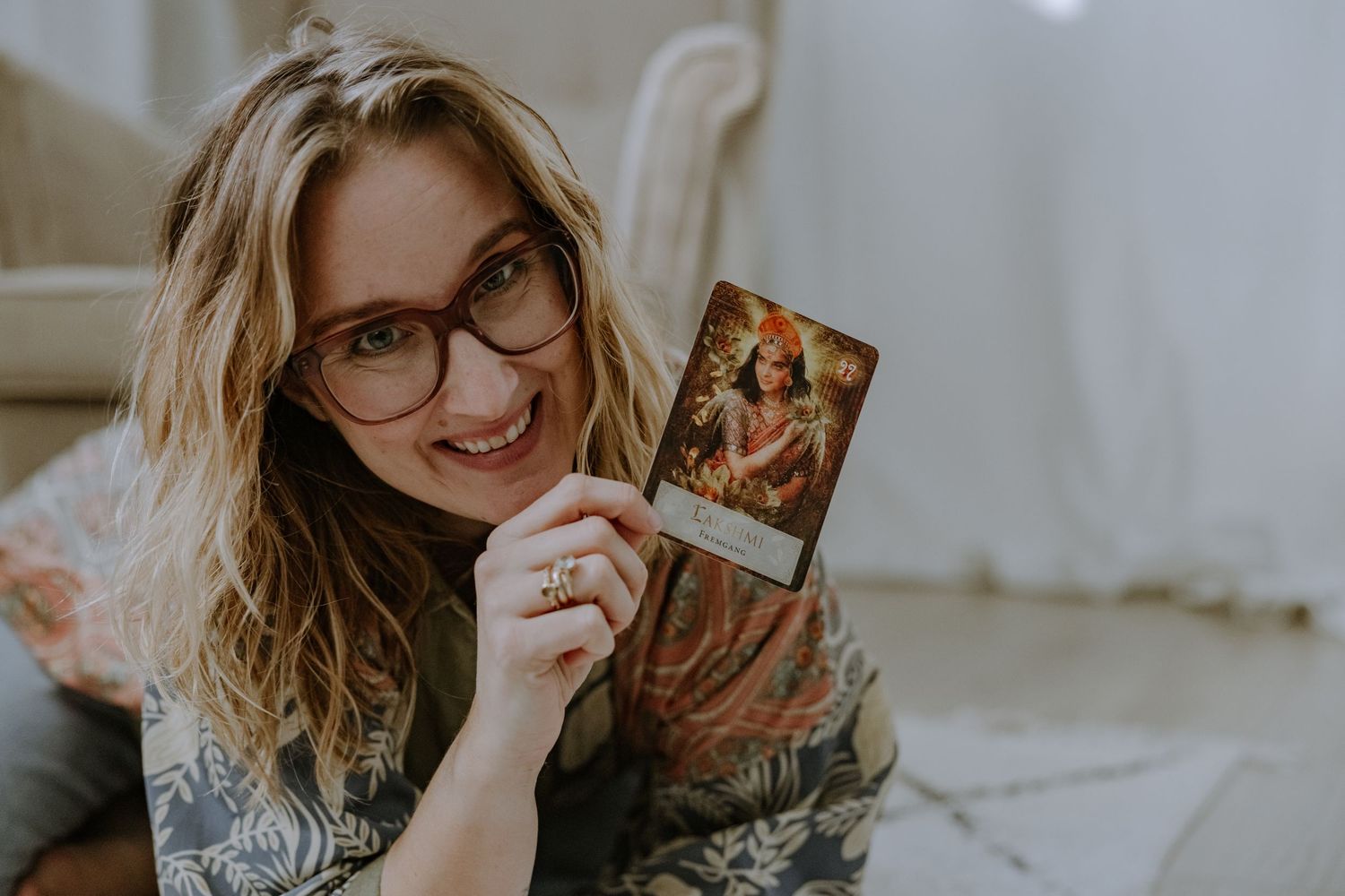 Person holding photo card while relaxing on patterned rug in cozy home setting.