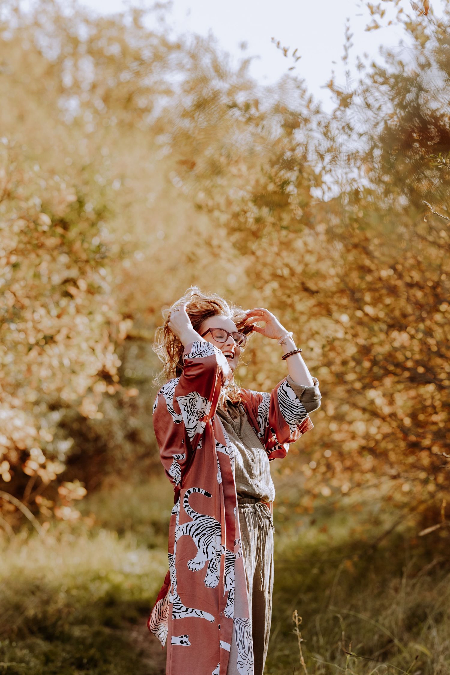 A figure in a floral kimono poses against golden autumn foliage.