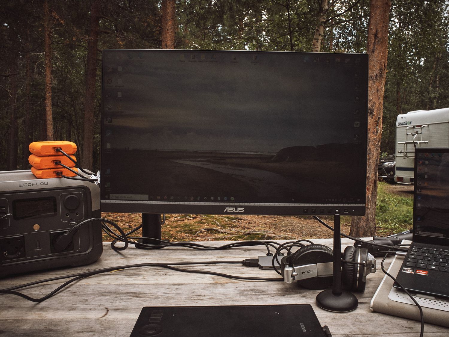 Outdoor movie setup with large projector screen and orange life preservers on rustic wooden deck in forest setting.