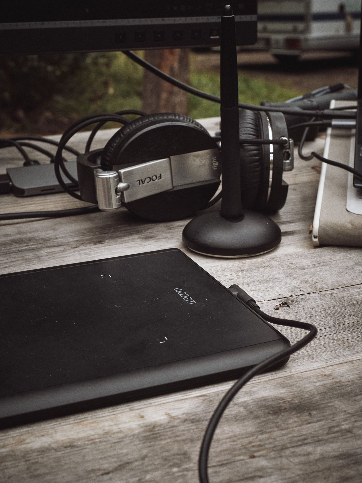 Professional headphones and microphone setup on wooden desk with laptop in moody lighting.