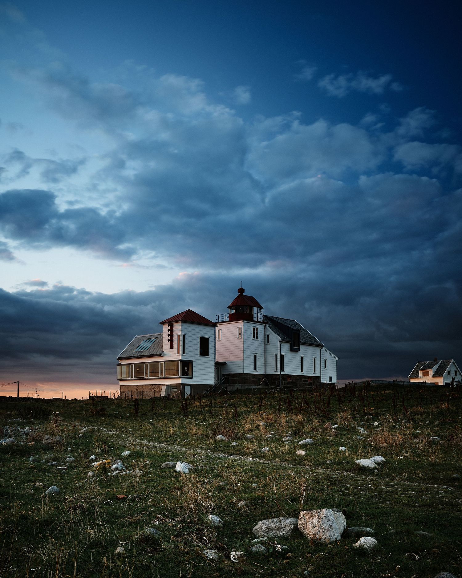 White buildings on rugged terrain under dramatic stormy skies at dusk.