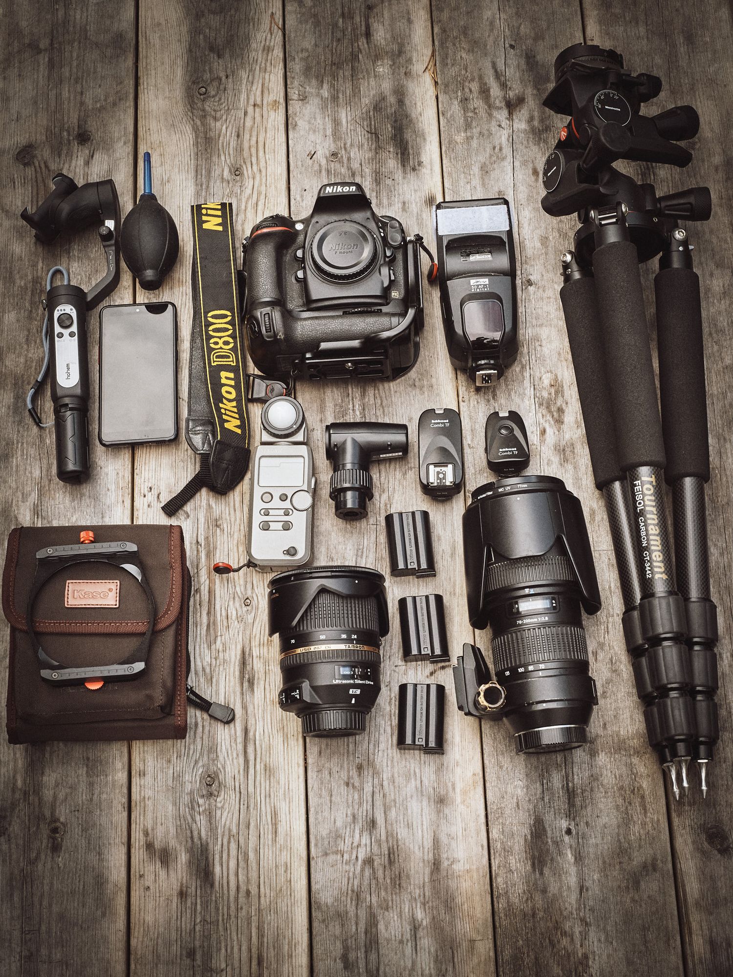 Professional photography gear including cameras, lenses, tripods and accessories laid out on rustic wooden planks.