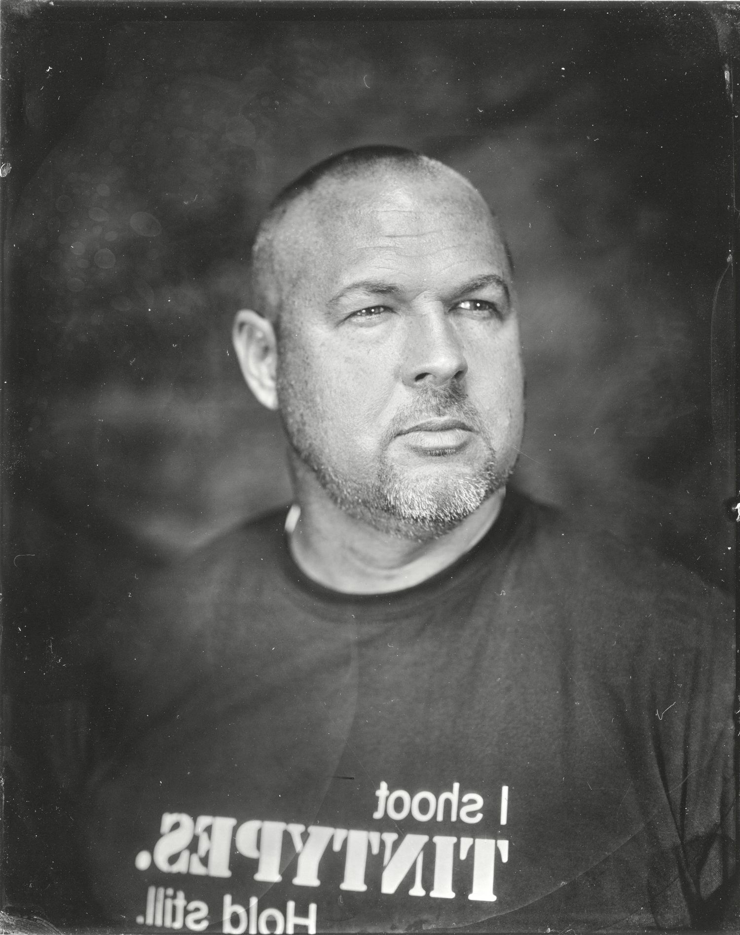 tintype portrait of Chris Morgan wearing shirt that says I shoot tintypes, hold still.