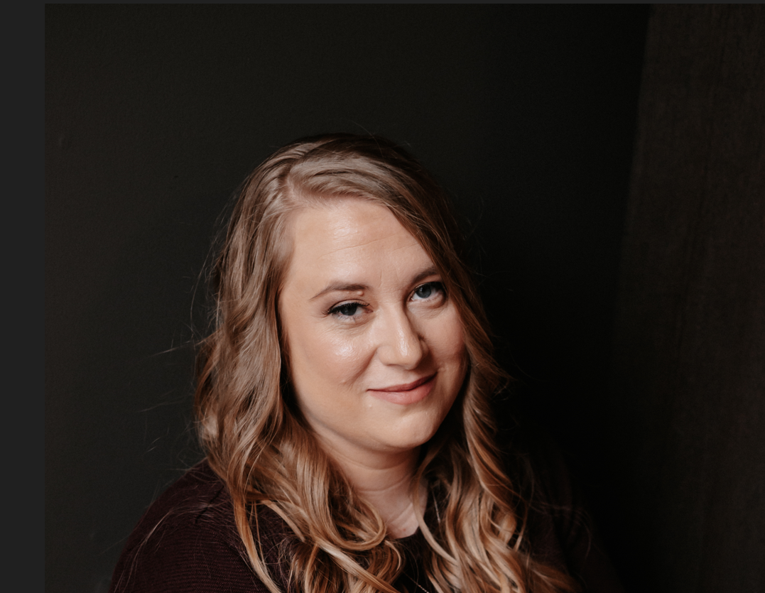 Warm toned portrait against dark background with soft side lighting.