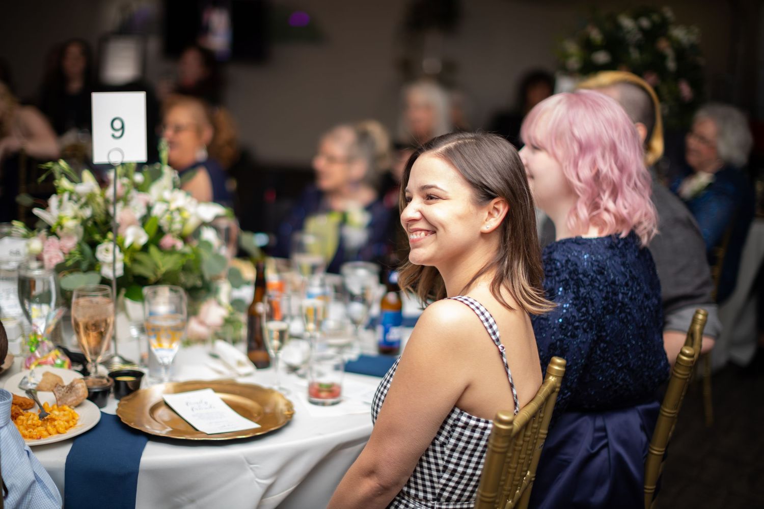 Guests enjoying a wedding reception at an elegant dinner table with floral centerpieces and table settings.