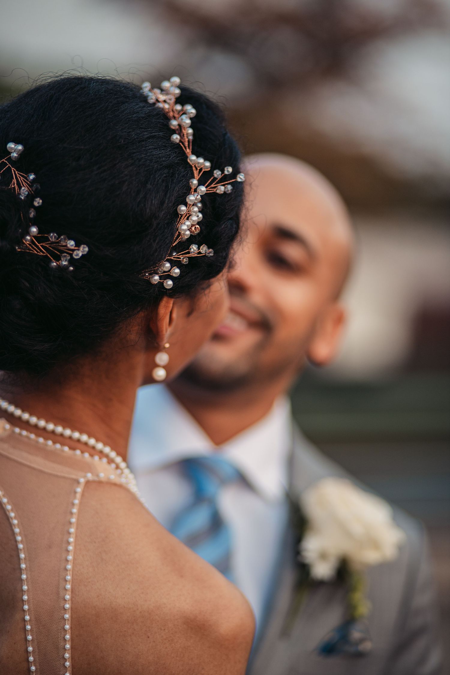 Delicate floral hairpiece and pearl neckline details captured in an intimate wedding portrait.