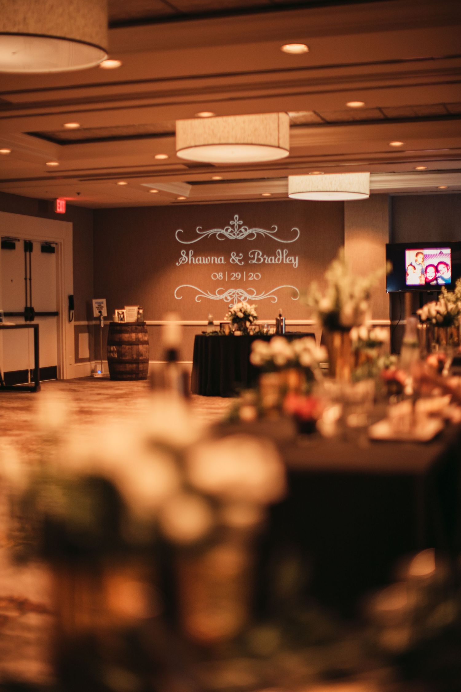Elegant ballroom reception setup with custom name projection and warm ambient lighting creating a romantic atmosphere.