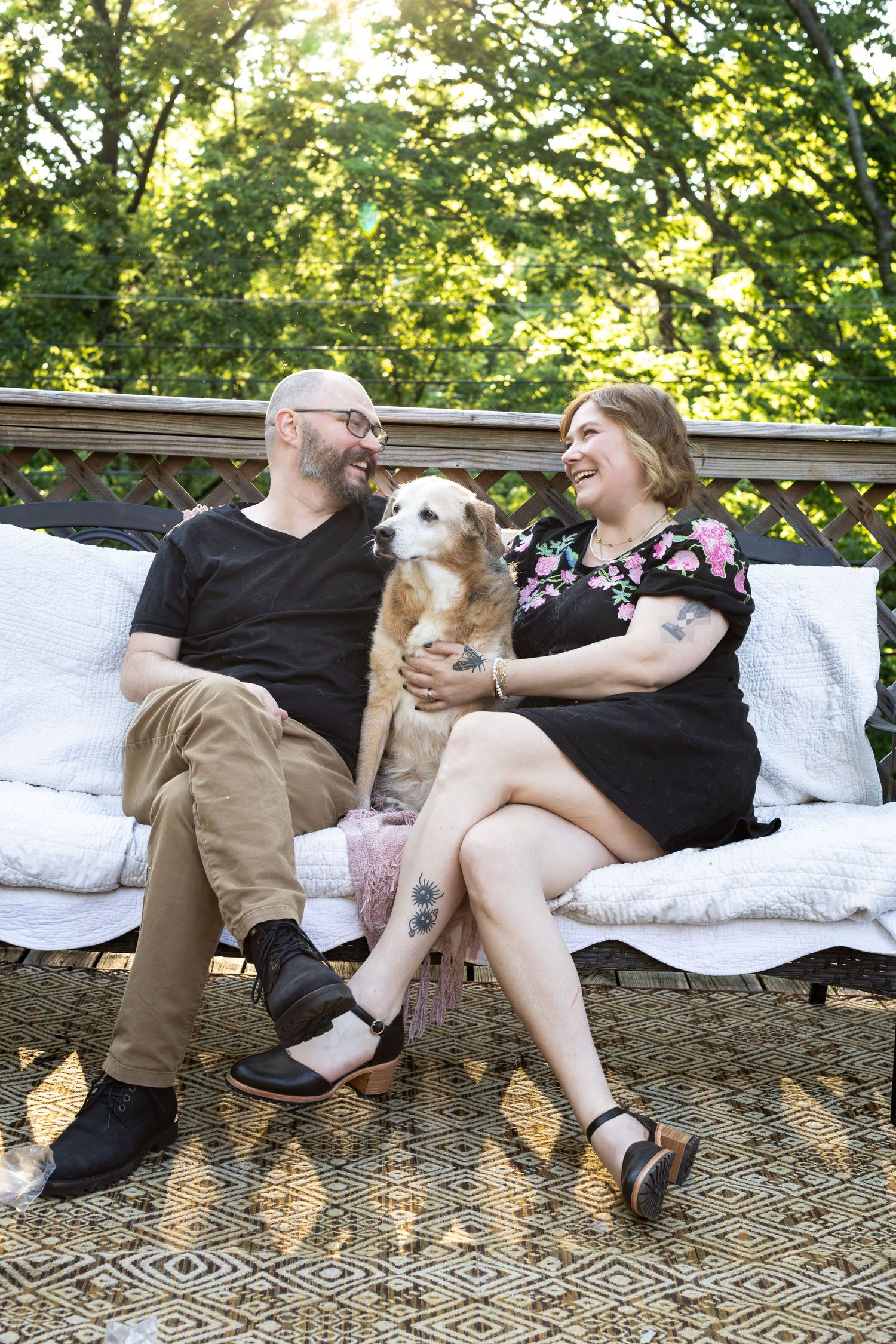 Couple relaxing outdoors with their small dog on a cozy outdoor couch.
