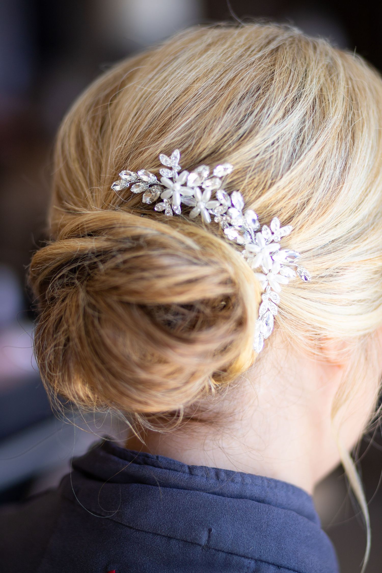 Elegant bridal hair accessory featuring delicate crystal and pearl floral design pinned into a blonde updo hairstyle.