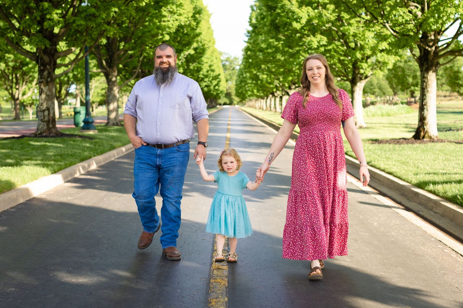 People in coordinated outfits walking together on a paved path in a lush green park setting during a sunny day.