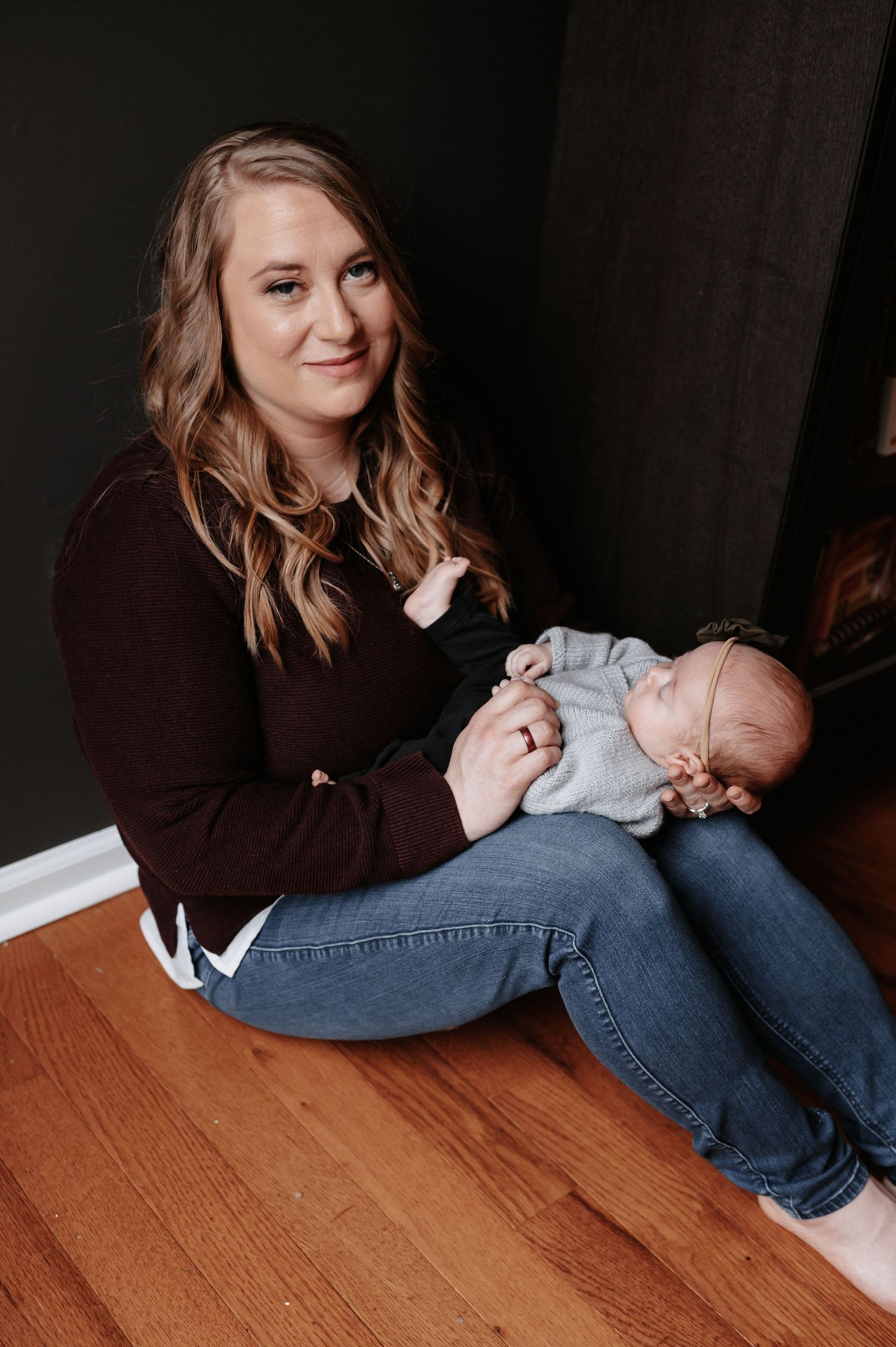A tender moment between mother and infant sitting on hardwood floor.