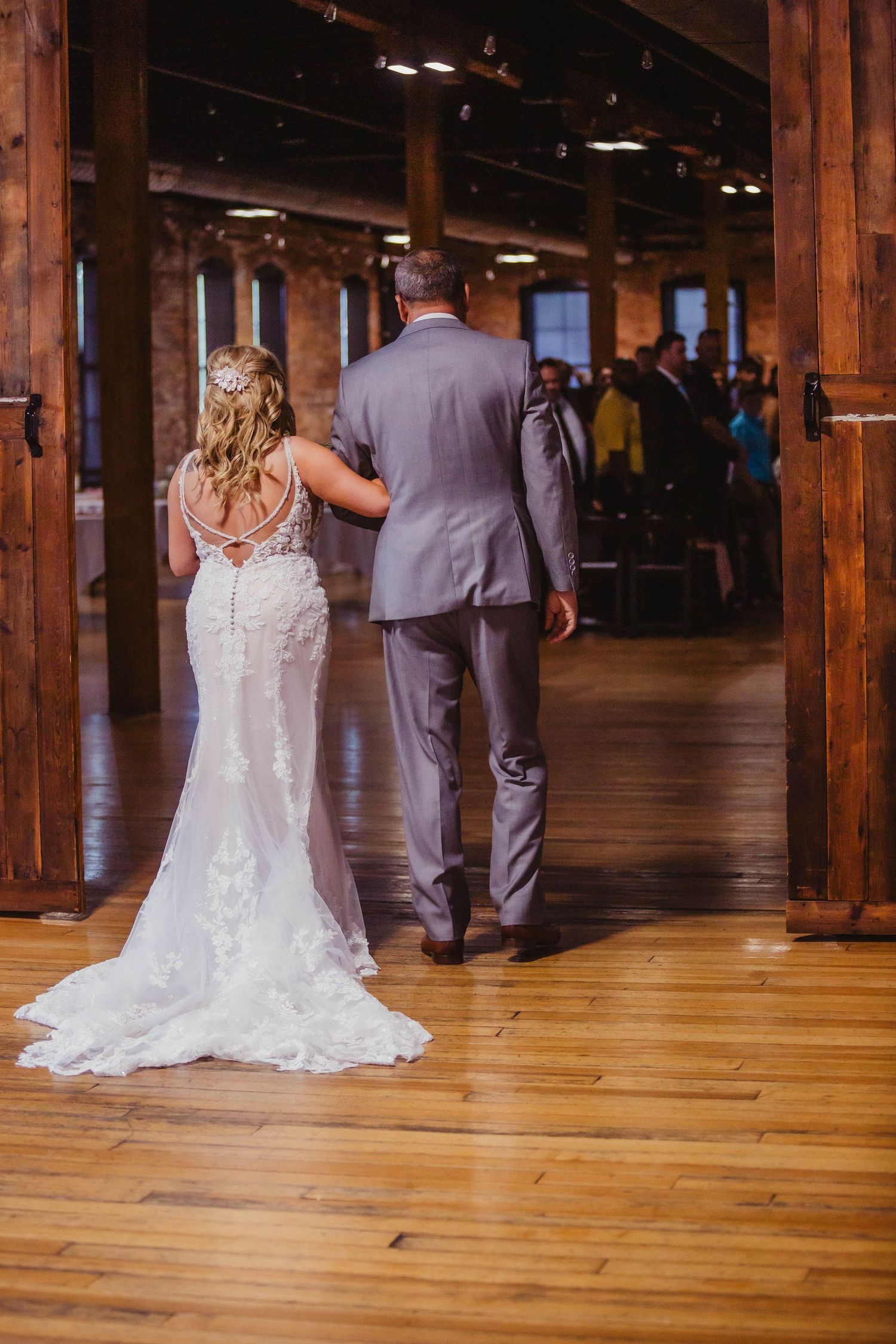 A couple enters their wedding reception venue through wooden doors.