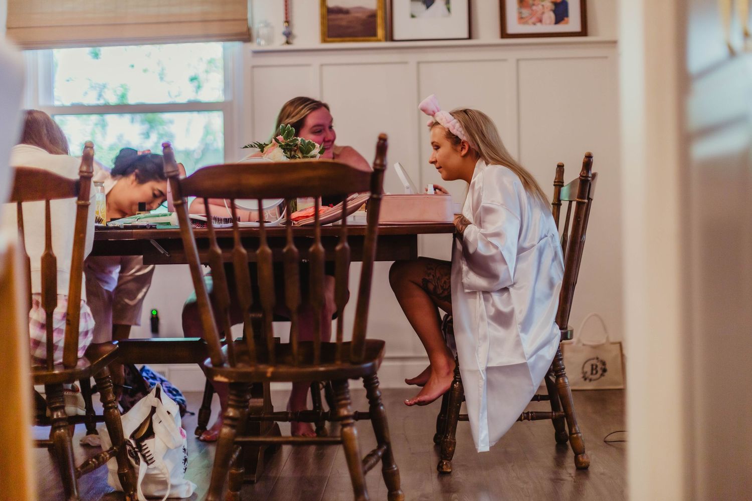Wedding preparation scene showing pink bridesmaid dresses hanging in a bright room with natural light.