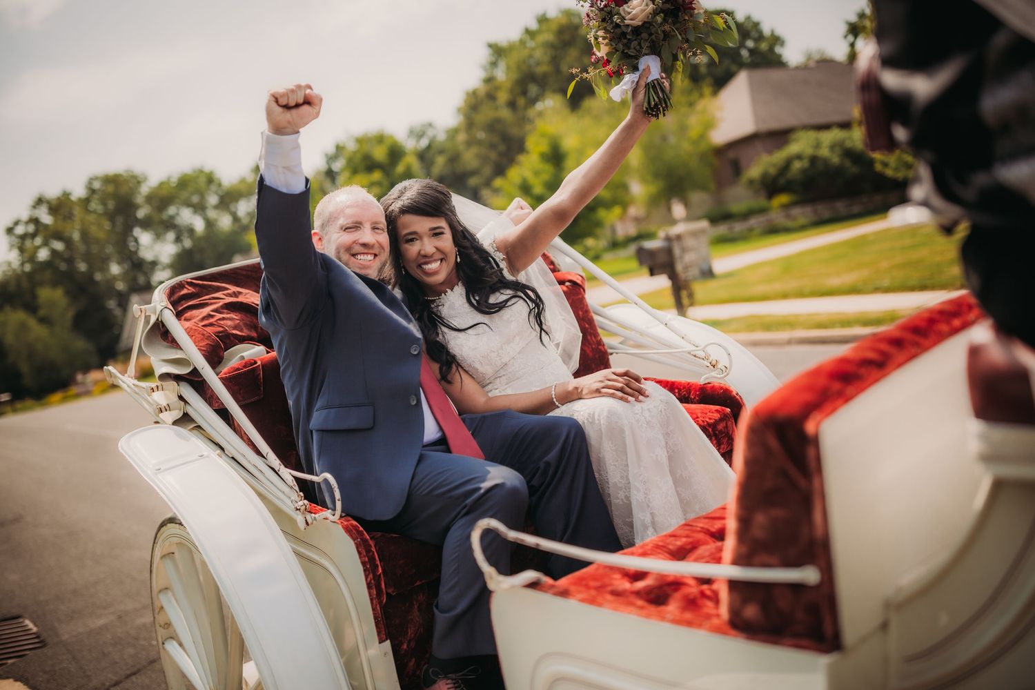 Newlyweds celebrate joyfully in a vintage convertible car on their wedding day.