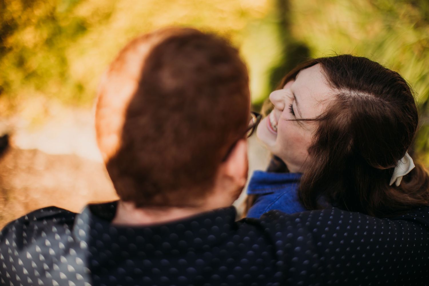 A close-up portrait of a couple sharing a tender moment in autumn sunlight.