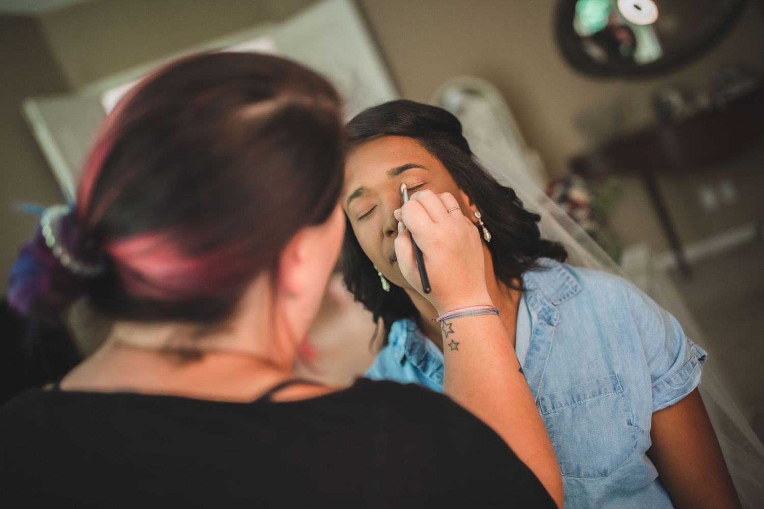 Professional makeup artist applying eye makeup during bridal preparation.