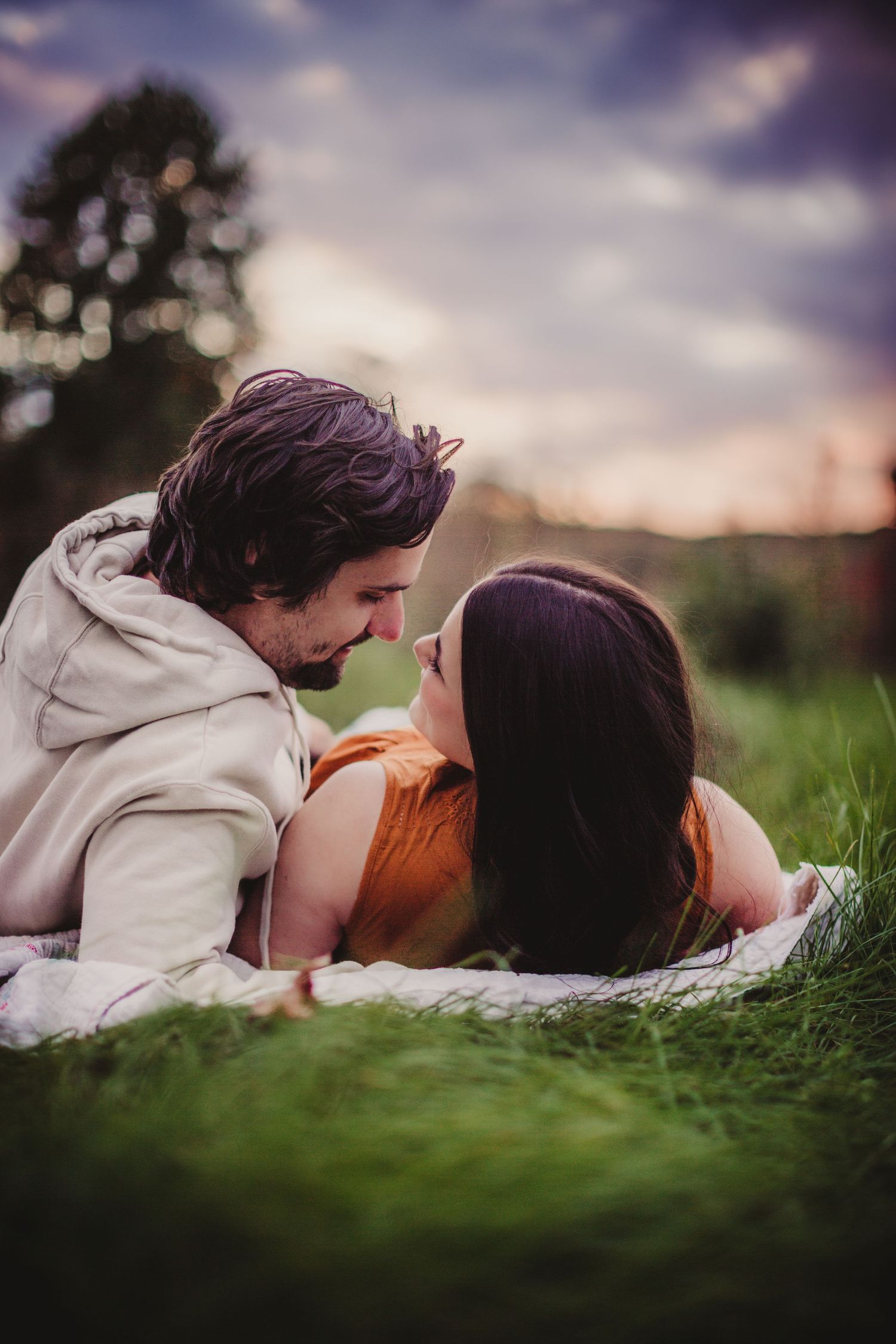 Artistic couple photography in lush green grass with moody sky backdrop.