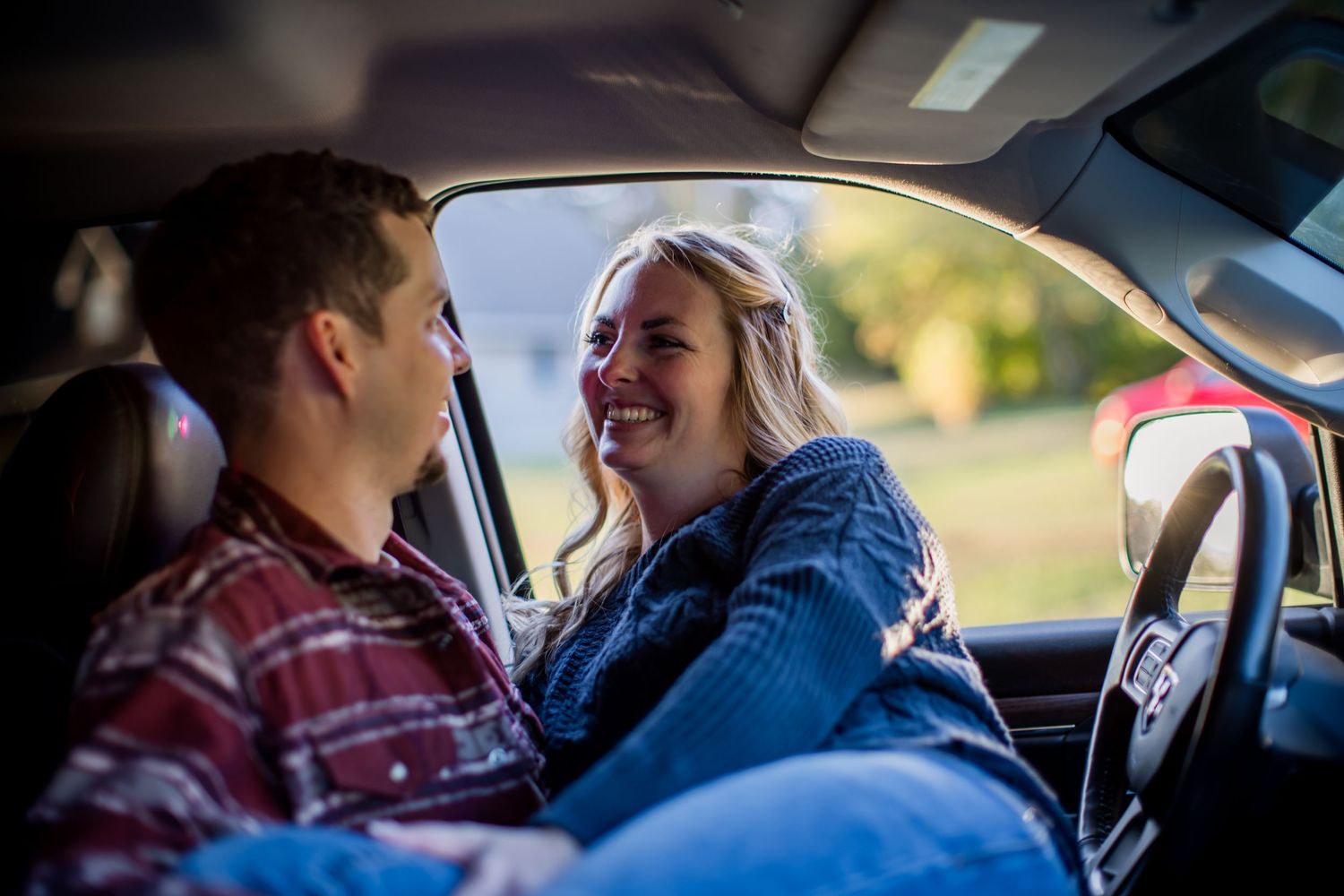 Couple sharing laughter together inside car during daytime.