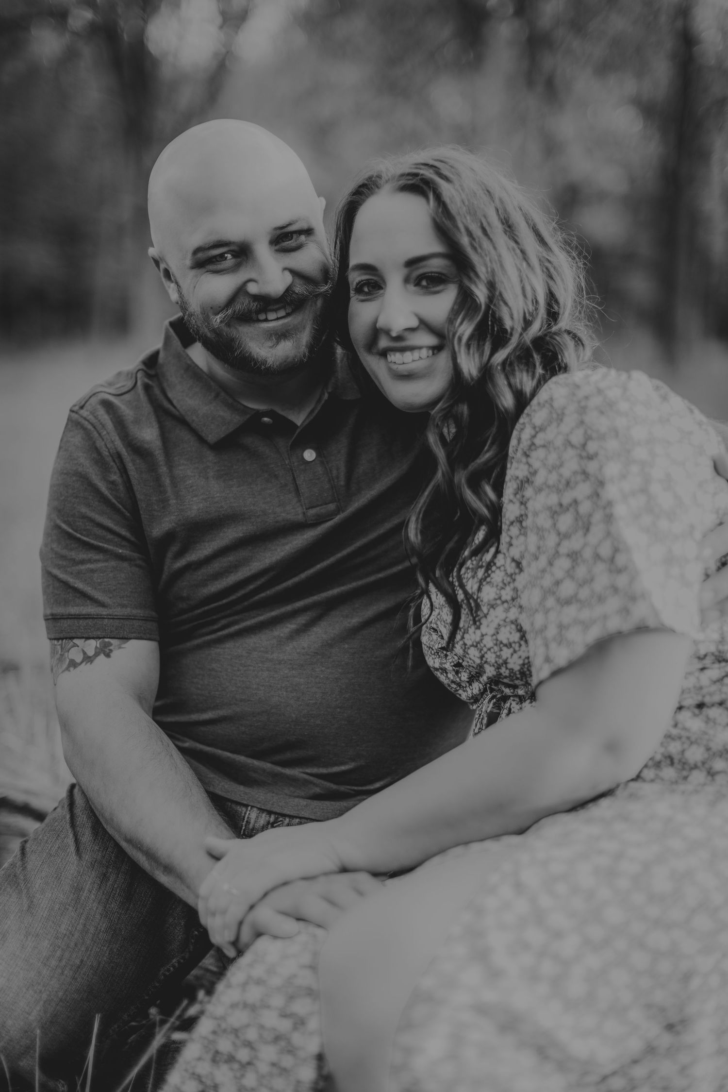 Black and white engagement photo of a happy couple embracing outdoors.