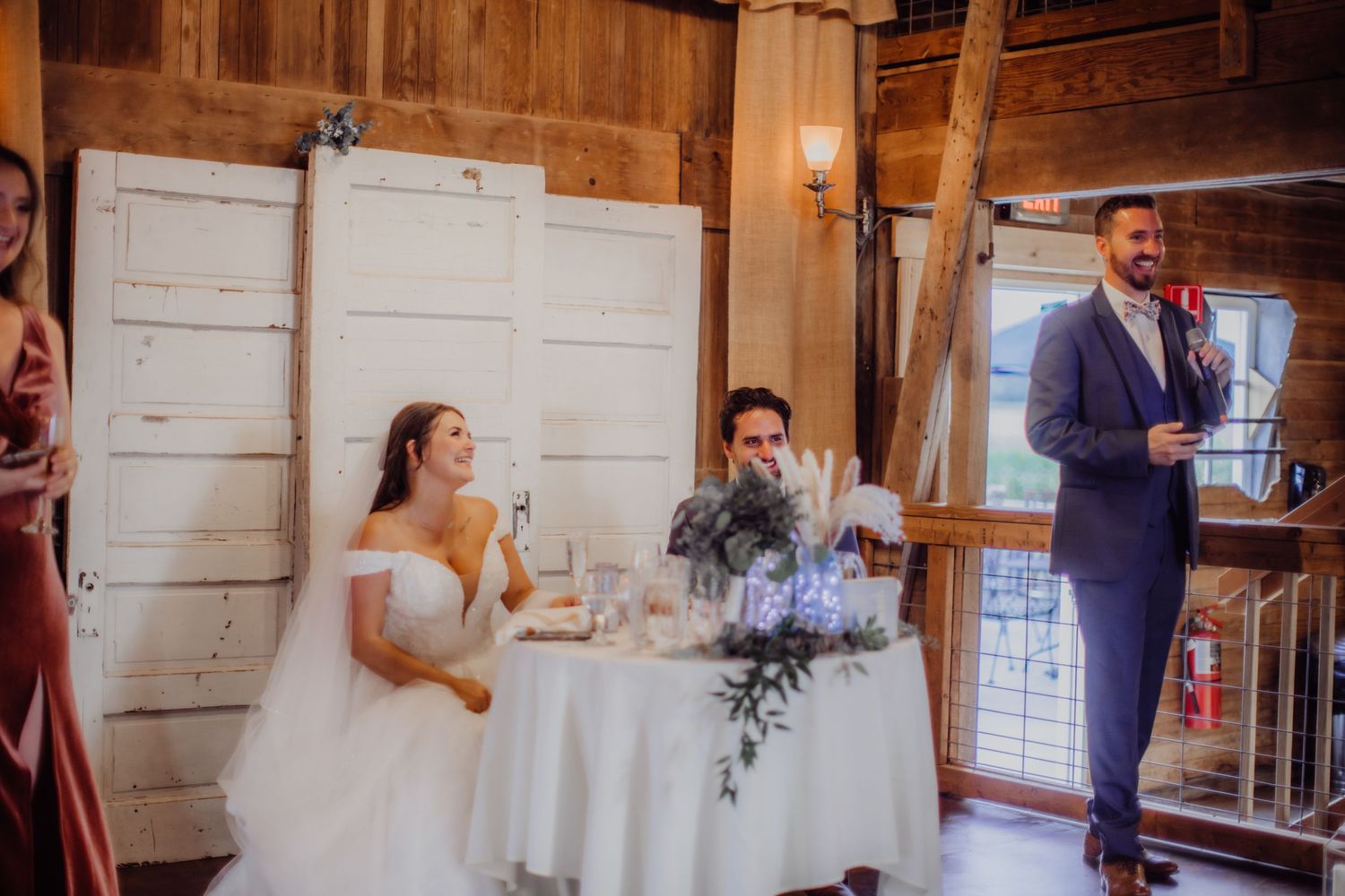 Wedding celebration inside a rustic barn venue with white walls and elegant decor.