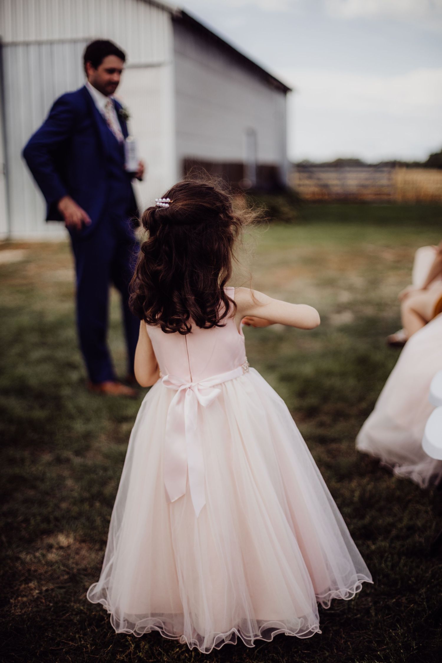 Little flower girl in a pink tulle dress with bow detail at a country wedding.