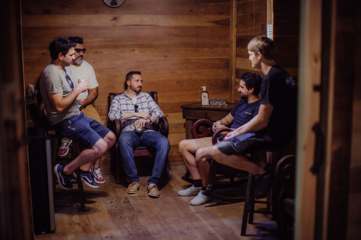 People relaxing in casual seating arrangement inside rustic wooden interior.