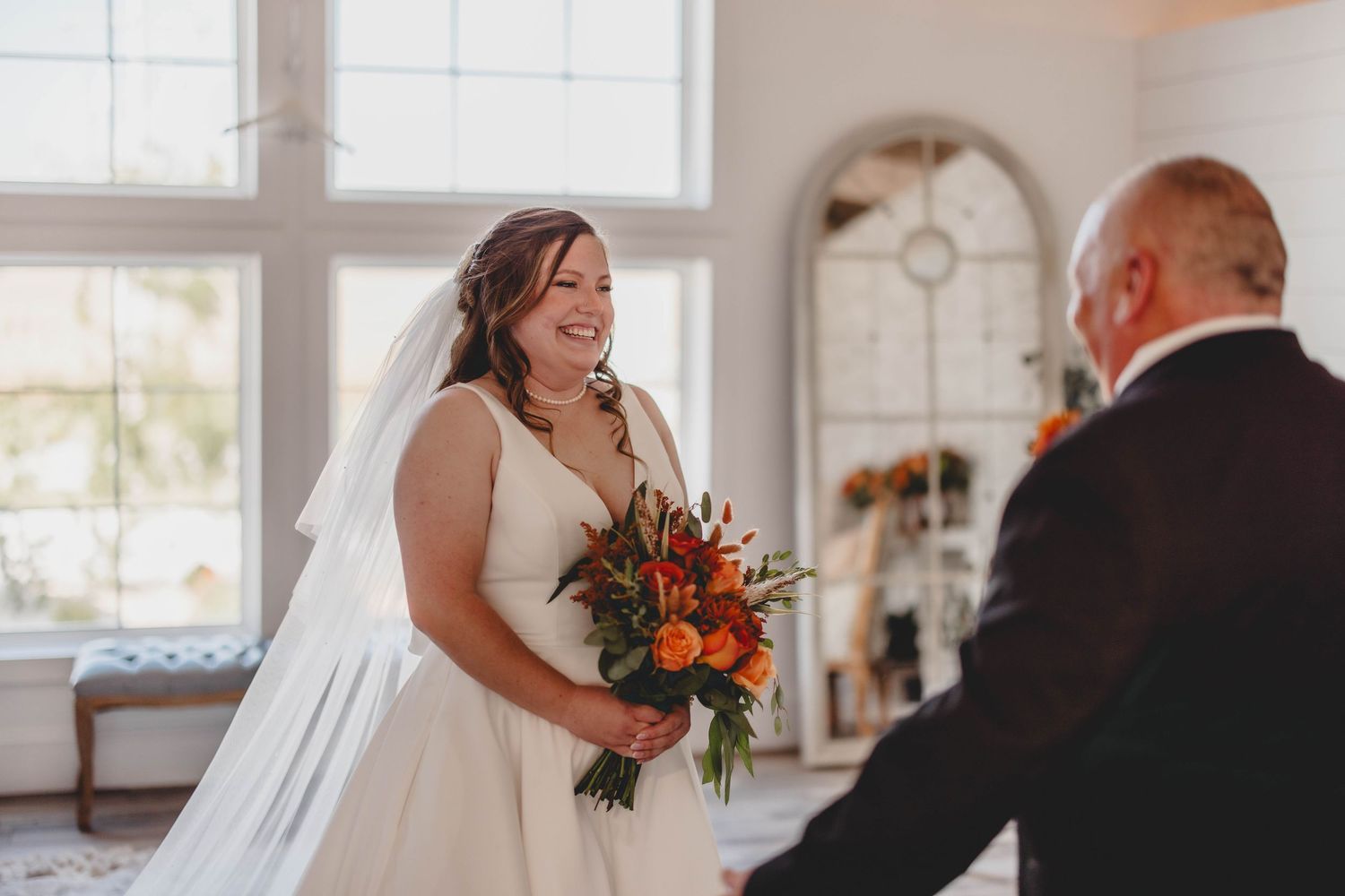 An intimate first look moment unfolds between a couple in a bright white room with classic decor.