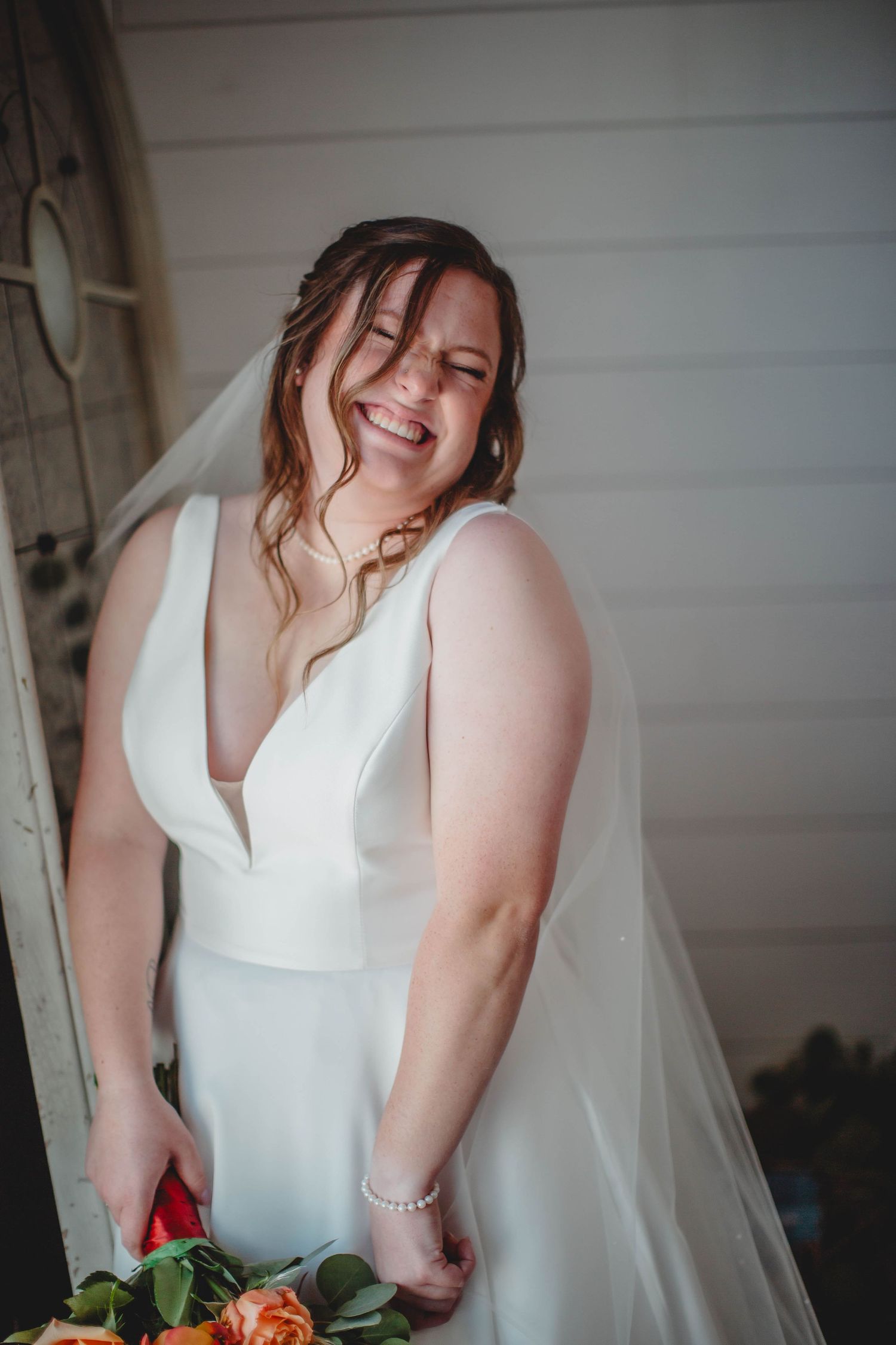 A natural, laughing moment captured during bridal portraits with an autumn bouquet.