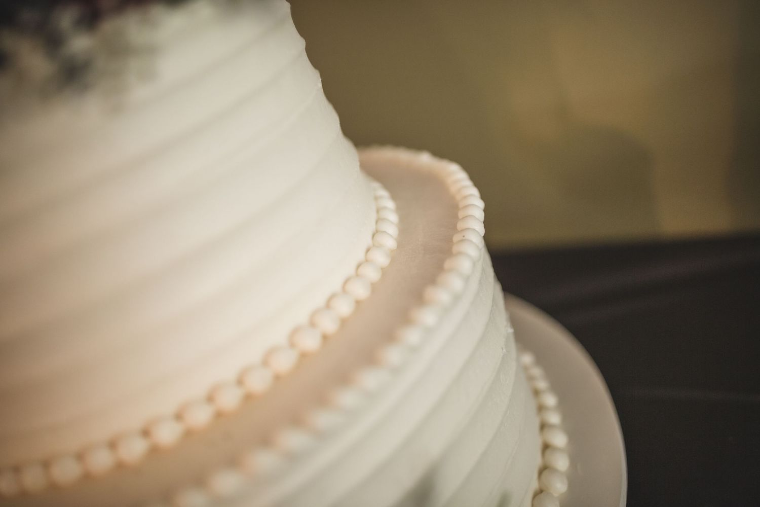 Detailed view of white wedding cake's pearl border decorations.