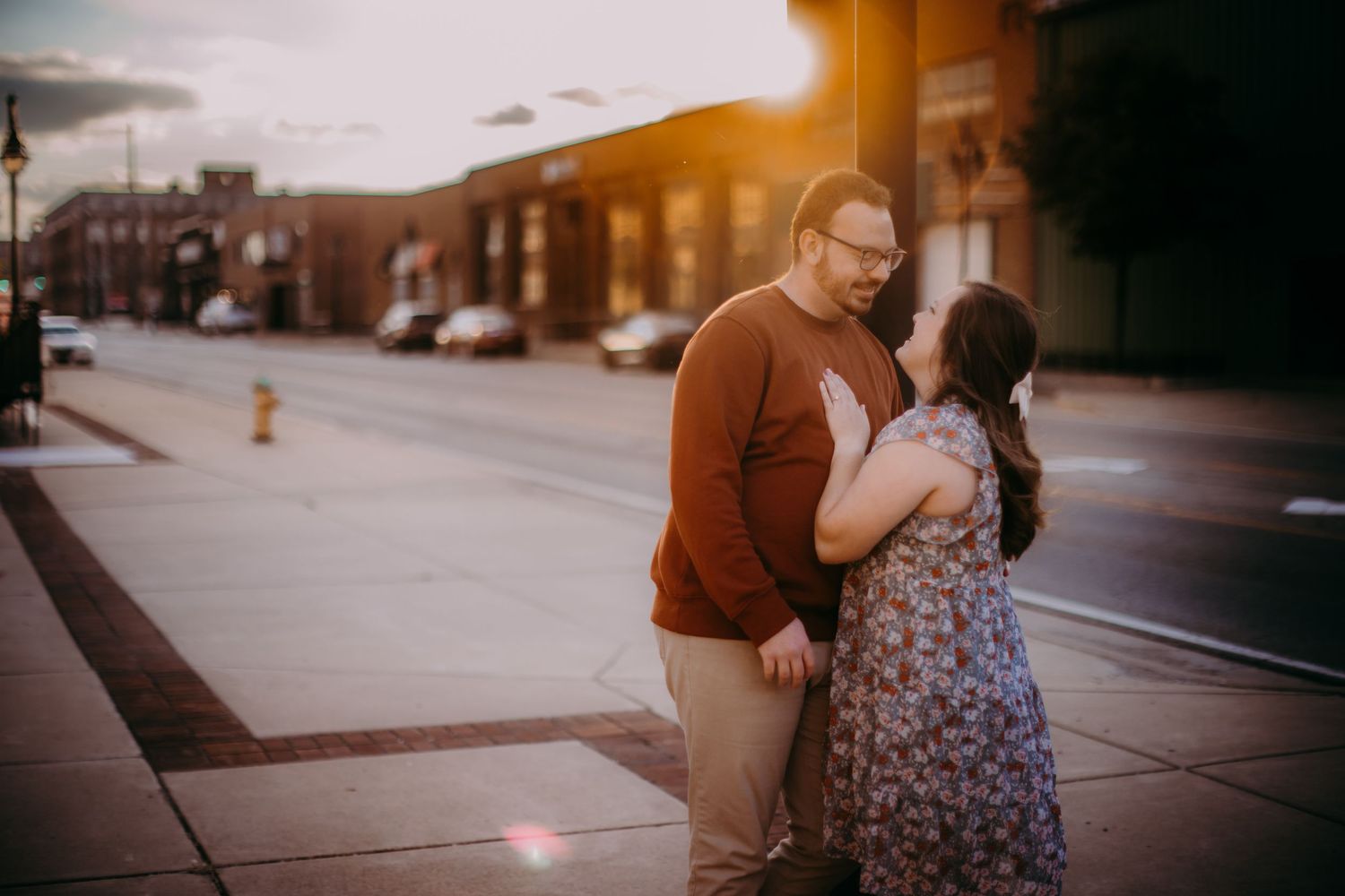 Sunset engagement photos capture an intimate moment between a couple on a downtown street.