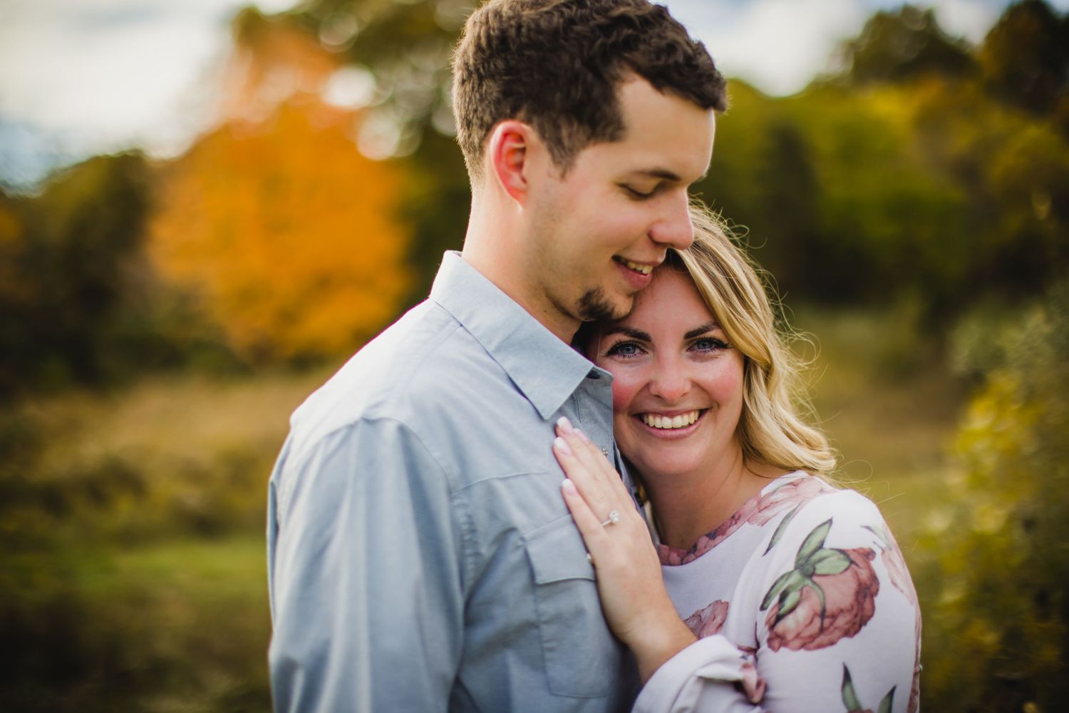 An intimate outdoor portrait of a couple sharing a joyful moment against autumn foliage.