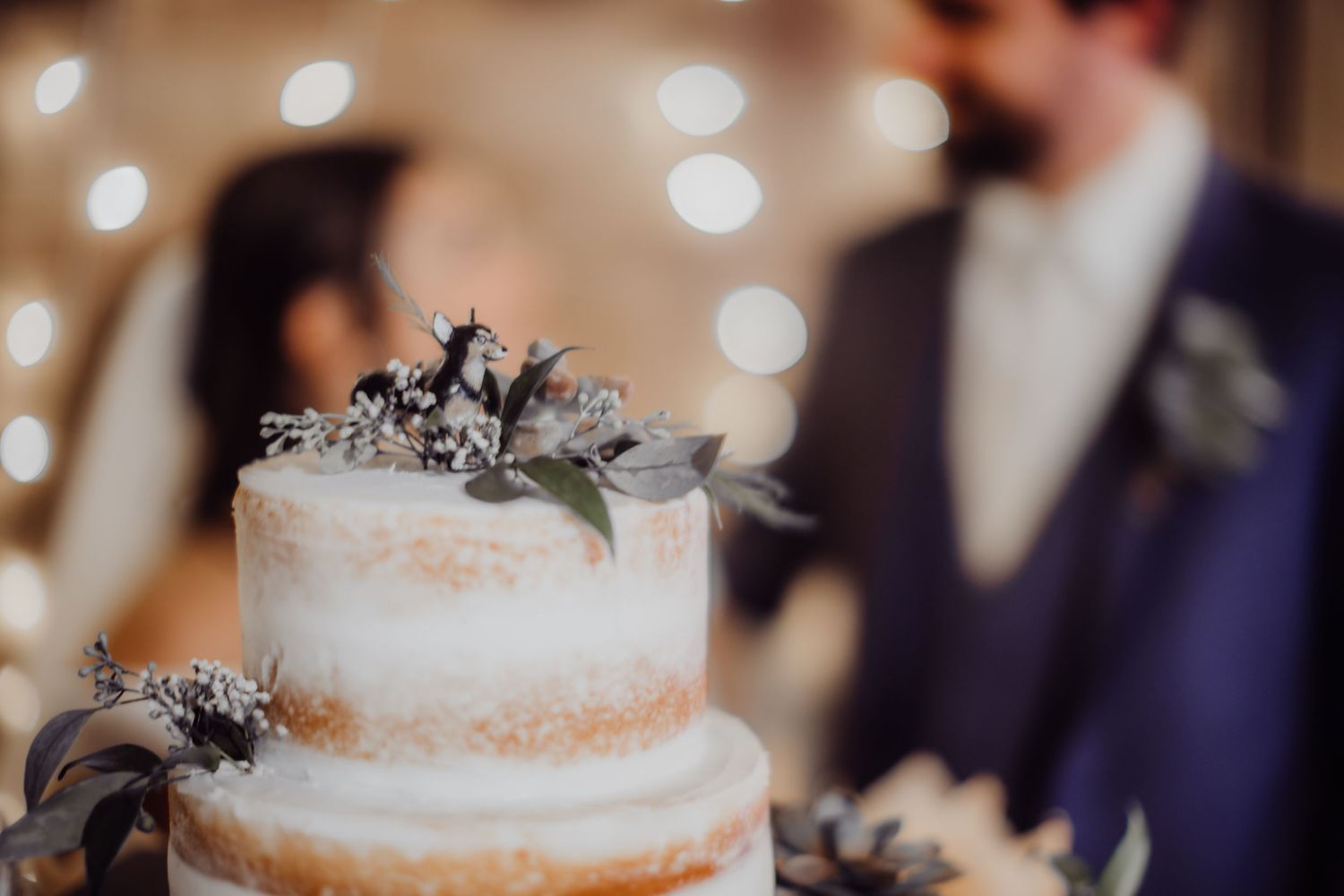 Close-up of an elegant white wedding cake decorated with grey floral accents.