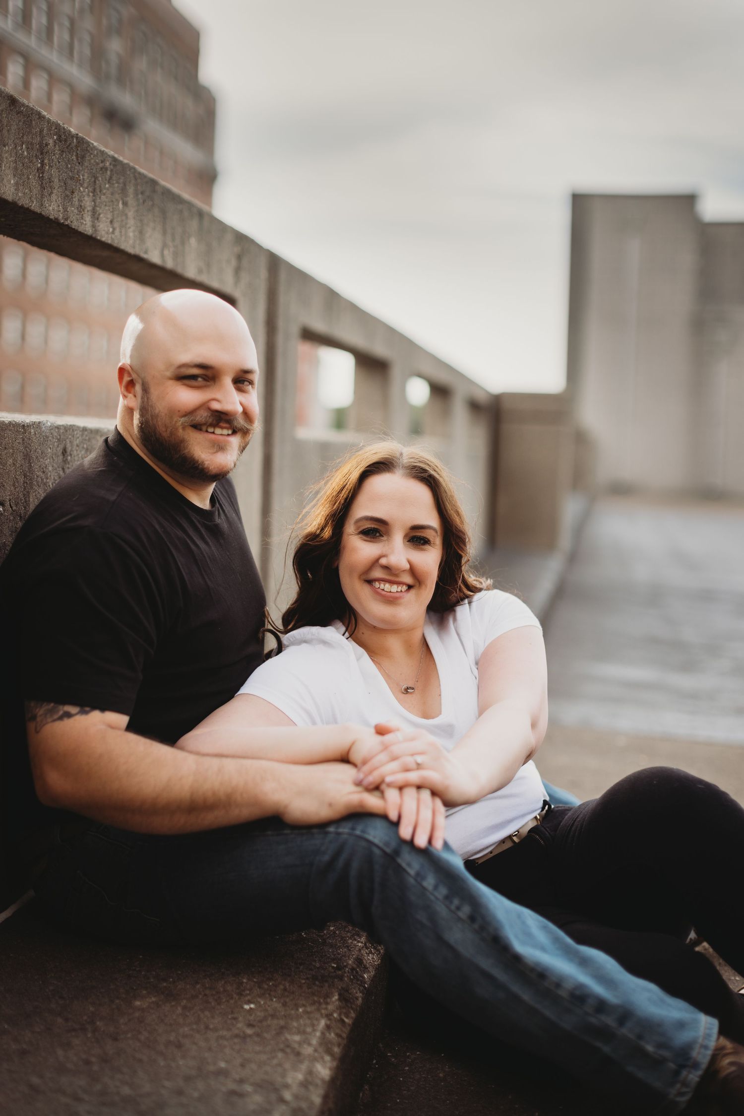 A couple relaxes and smiles together during an outdoor photography session.