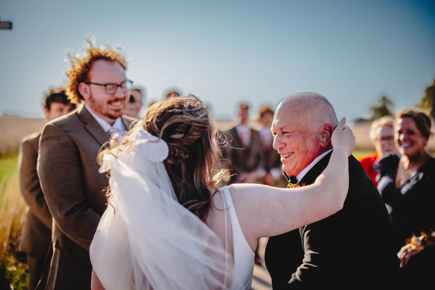 Joyful celebration during outdoor wedding ceremony under white pergola.