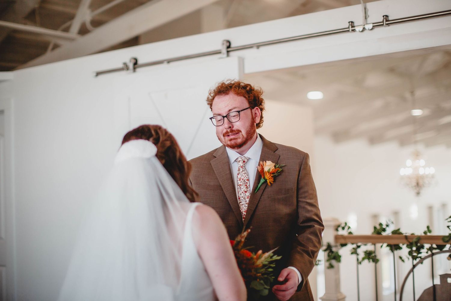 A spacious wedding venue with white walls and decorative floral arrangements.