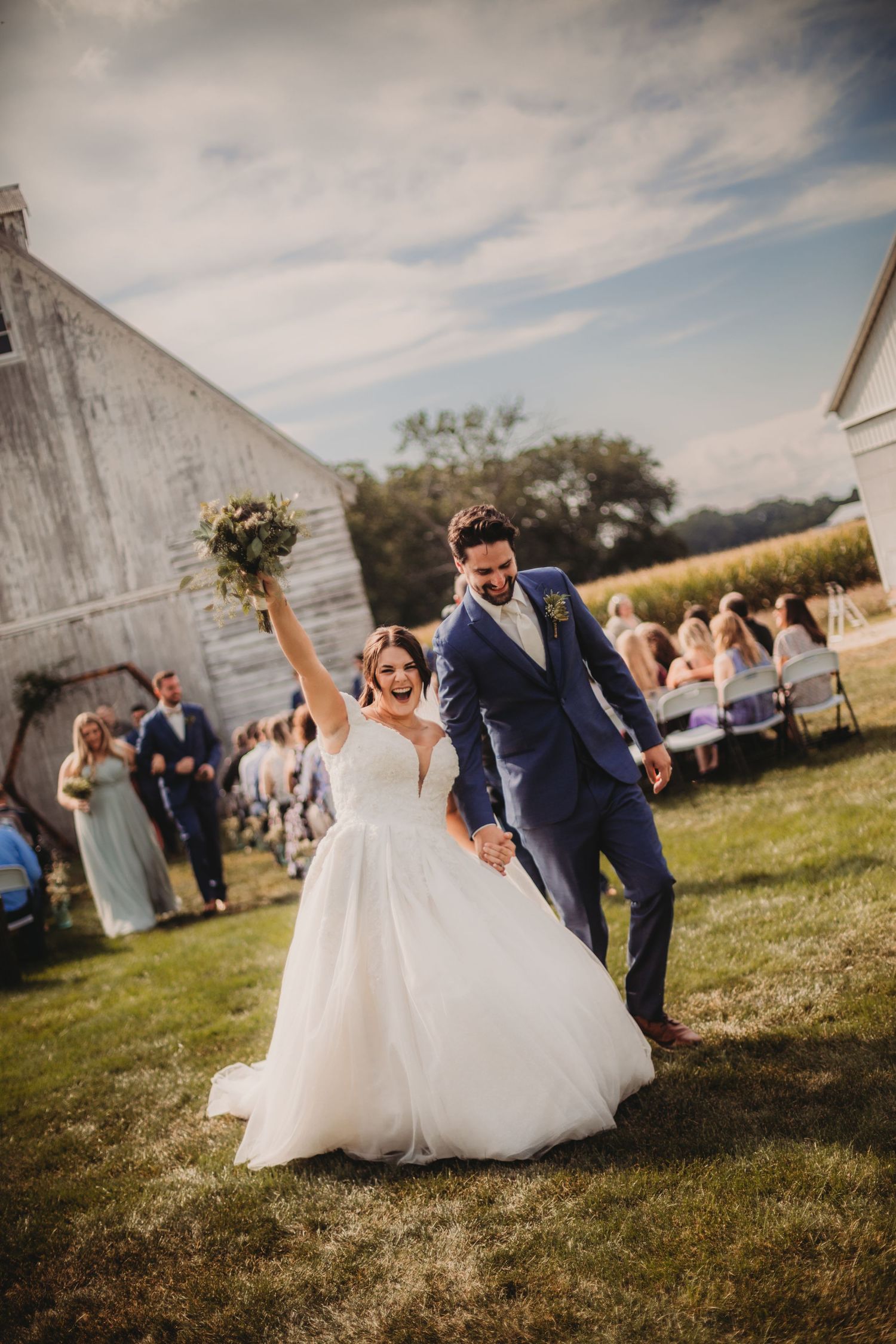 Candid wedding photography moments captured outside vintage barn during outdoor celebration.