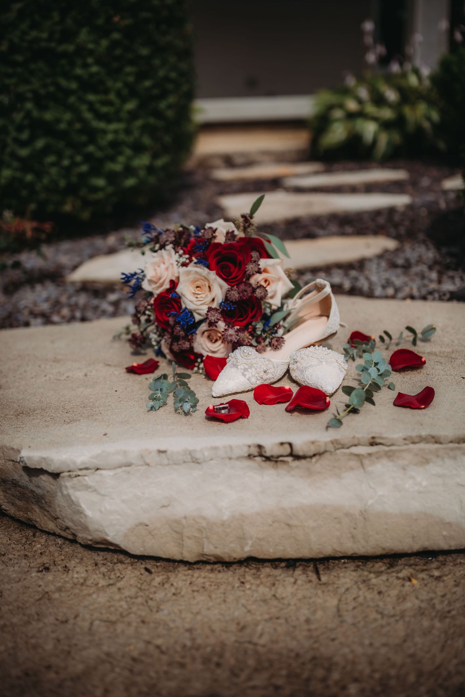 Romantic wedding details featuring patriotic-colored bouquet and lace flats on outdoor stone steps.